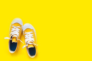 Sarı bir arka plan üzerinde kısa düşük parlak spor ayakkabı.
