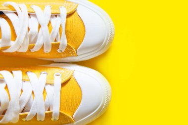 Sarı bir arka plan üzerinde kısa düşük parlak spor ayakkabı.