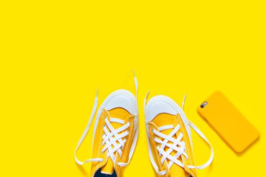 Sarı bir arka plan üzerinde kısa düşük parlak spor ayakkabı.