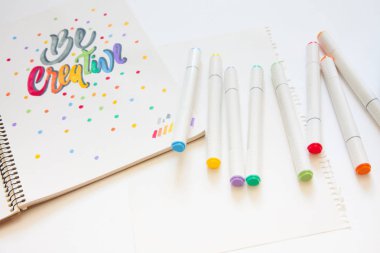 grafik tasarım, el yazısı, yaratma kavramı. ihale küçük elleri kadın ressam süs süslü harfler beyaz çizgili kağıt üzerinde keçeli kalemler ile inscribing.