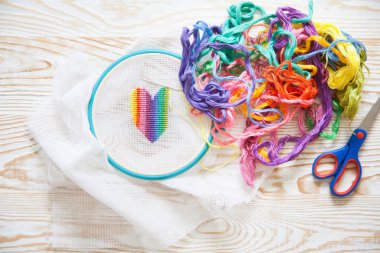 Kalp beyaz tuval üzerine bir çarpı işlemeli. Gökkuşağı konu. Beyaz arka plan. İğne ve makas.