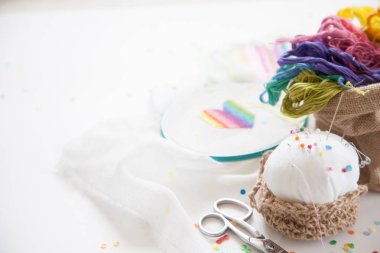 Kalp beyaz tuval üzerine bir çarpı işlemeli. Gökkuşağı konu. Beyaz arka plan. İğne ve makas.