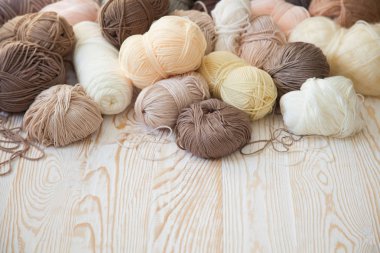 İplik olduğunu bej, kahverengi, gri ve beyaz. Arka plan yaşlı ahşap. İğneler, makas, kahve, örgü, örgü örme kumaş.