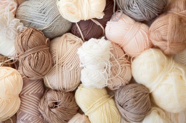 İplik olduğunu bej, kahverengi, gri ve beyaz. Arka plan yaşlı ahşap. İğneler, makas, kahve, örgü, örgü örme kumaş.