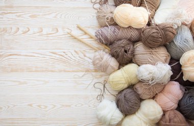 İplik olduğunu bej, kahverengi, gri ve beyaz. Arka plan yaşlı ahşap. İğneler, makas, kahve, örgü, örgü örme kumaş.