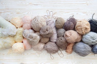 İplik olduğunu bej, kahverengi, gri ve beyaz. Arka plan yaşlı ahşap. İğneler, makas, kahve, örgü, örgü örme kumaş.