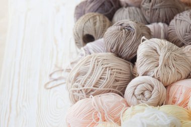 İplik olduğunu bej, kahverengi, gri ve beyaz. Arka plan yaşlı ahşap. İğneler, makas, kahve, örgü, örgü örme kumaş.