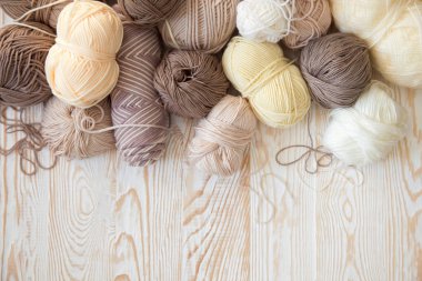 İplik olduğunu bej, kahverengi, gri ve beyaz. Arka plan yaşlı ahşap. İğneler, makas, kahve, örgü, örgü örme kumaş.