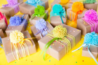 Renkli kurdeleler ve ponpon ile renkli hediye kutuları. Sarı geri