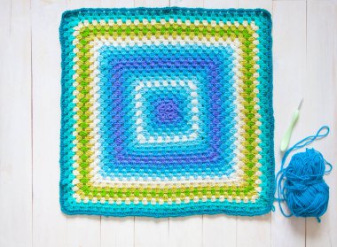 Tığ işi kumaş kare. Ahşap arka plan beyaz. Örgü kavramı