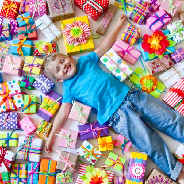 子供にはプレゼントが散らばっています。少年が床にあると — ストック写真