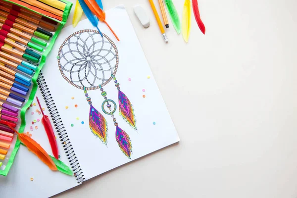 Uma menina desenha um apanhador de sonhos com marcadores coloridos . — Fotografia de Stock