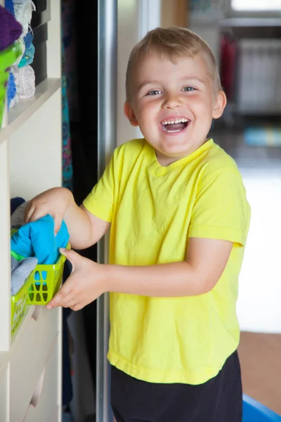 The child puts his clothes on. The boy pulls the T-shirt out of — Stock Photo, Image