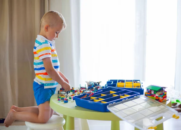 Маленький Блондин Играет Кучей Разноцветных Пластиковых Блоков Помещении Блоки Лего — стоковое фото