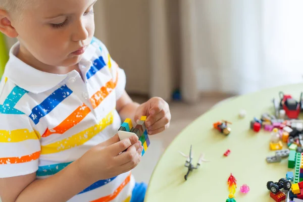 Pequeño niño rubio jugando con un montón de bloques de plástico de colores — Foto de Stock