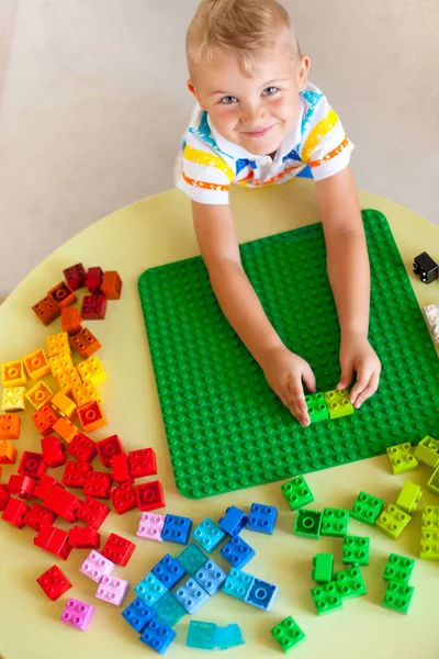 Blond kind jongetje spelen met veel kleurrijke plastic blok — Stockfoto