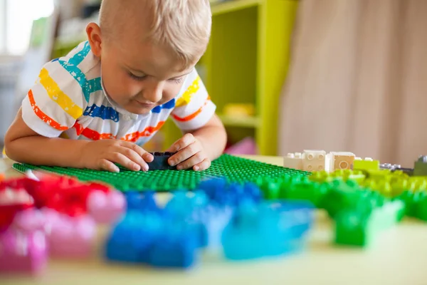 Blond kind jongetje spelen met veel kleurrijke plastic blok — Stockfoto