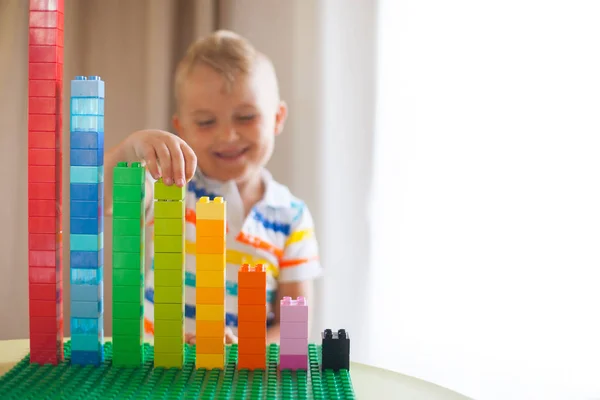 Malý blonďatý kluk hrát se spoustou barevných plastových bloku — Stock fotografie