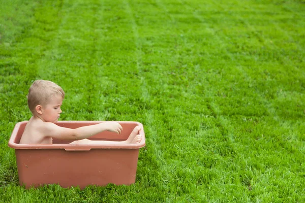 Bambino si lava in bagno sull'erba verde. Ragazzo 4-5 anni — Foto Stock