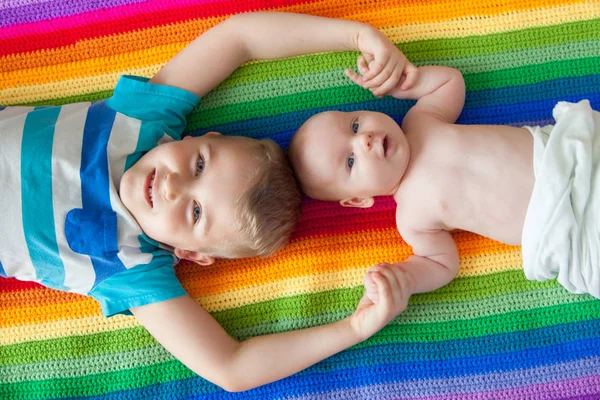 男孩们躺着 面带微笑 手牵手 彩虹毯 年龄较大和更年轻的兄弟 — 图库照片