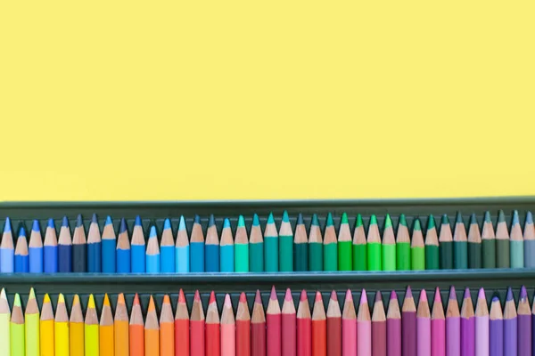 Colorful bright pencils for drawing pictures and sketches. On white and yellow background. top view