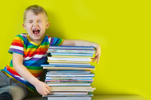 Il bambino tiene in mano una grande pila di libri per bambini. — Foto Stock