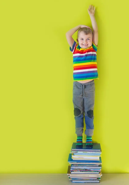 Un gioioso bambino sorridente è in piedi su una pila di bo per bambini — Foto Stock