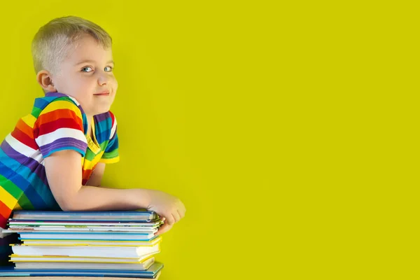 Il bambino tiene in mano una grande pila di libri per bambini. — Foto Stock