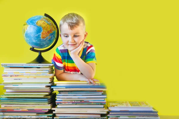 Il ragazzo siede accanto ai libri per bambini e al globo. Verde b — Foto Stock