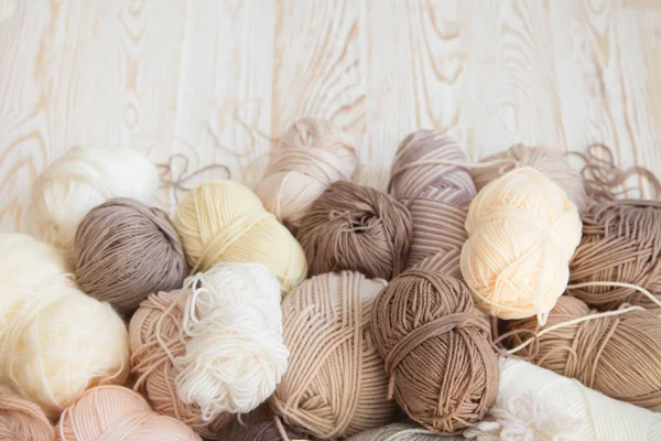 İplik olduğunu bej, kahverengi, gri ve beyaz. Arka plan yaşlı ahşap. İğneler, makas, kahve, örgü, örgü örme kumaş.