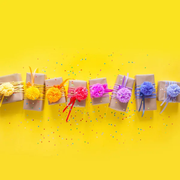 Caixas de presente coloridas com fitas coloridas e pompon. Amarelo de volta — Fotografia de Stock