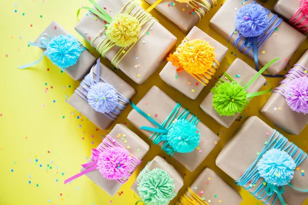 Caixas de presente coloridas com fitas coloridas e pompon. Amarelo de volta — Fotografia de Stock