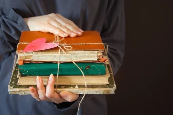 Το κορίτσι κρατά μια στοίβα των παλαιών βιβλίων στα χέρια της. Κλιμακωτά wi — Φωτογραφία Αρχείου