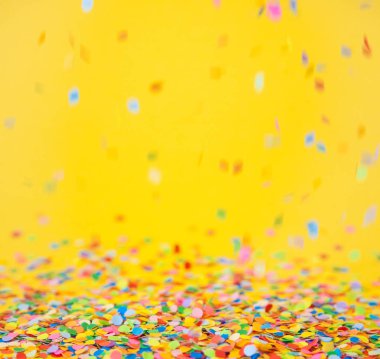 Renkli konfeti sarı arka plan üzerinde uçan