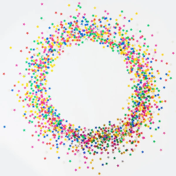Cornice rotonda realizzata con stelle coriandoli colorate. Sfondo bianco. Fe — Foto Stock