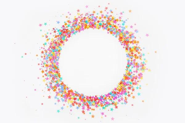 Round frame made of colored confetti stars. White background. Fe — Stock Photo, Image