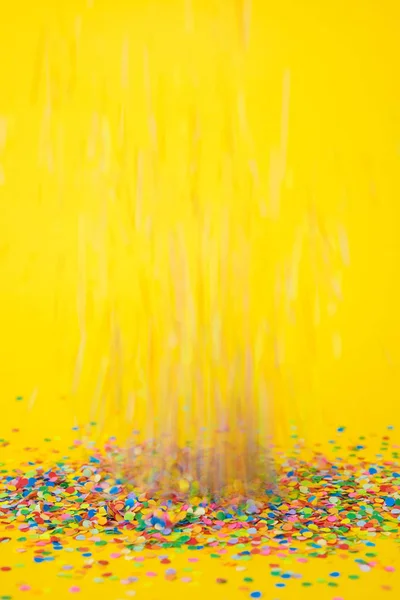 Renkli konfeti sarı arka plan üzerinde uçan — Stok fotoğraf