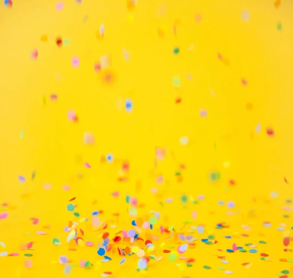 Kolorowy konfetti Latanie na żółtym tle — Zdjęcie stockowe