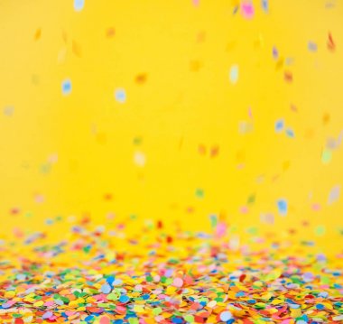 Renkli konfeti sarı arka plan üzerinde uçan