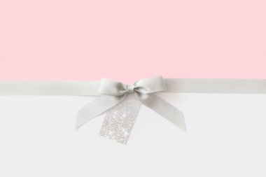 Beyaz ve pembe bir backgroun bir hediye olarak bir yay ile Gümüş kurdele