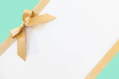 Beyaz ve nane arka plan üzerinde bir hediye olarak bir yay ile Altın kurdele