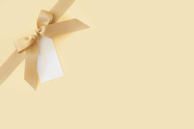 Bej arka planda hediye olarak bir yay ile Altın kurdele