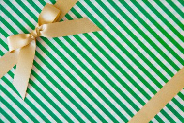 Beyaz ve yeşil arka planda hediye olarak bir yay ile Altın kurdele