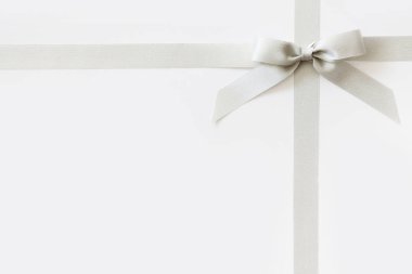 Beyaz arka plan üzerinde bir hediye olarak bir yay ile Gümüş kurdele