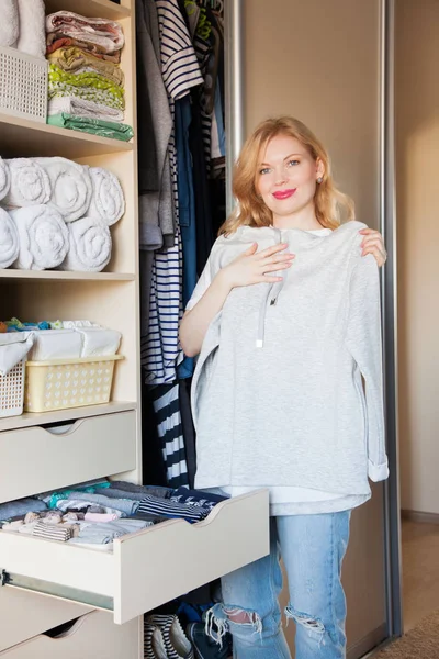 La chica está considerando un vestido a rayas. Que cuelga en la sala — Foto de Stock