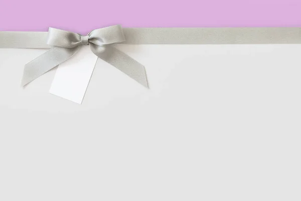 Cinta de plata con un lazo como regalo en un fondo blanco y violeta — Foto de Stock