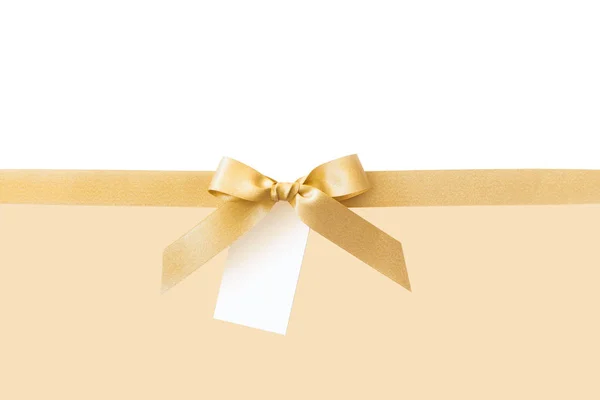 Złota wstążka z kokardą jako prezent na białym i beżowym tle — Zdjęcie stockowe