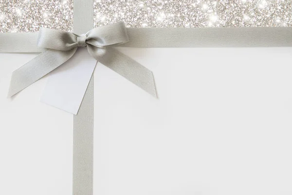 银丝带与蝴蝶结作为礼物在白色和闪亮的后沟 — 图库照片