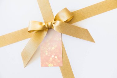 Beyaz bir arka plan üzerinde bir hediye olarak bir yay ile altın kurdele. Boş pa
