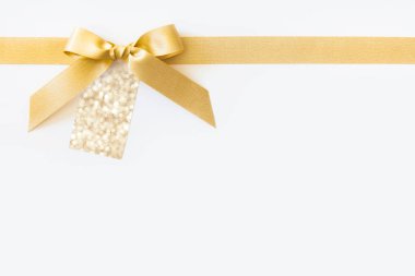 Beyaz bir arka plan üzerinde bir hediye olarak bir yay ile altın kurdele. Boş pa